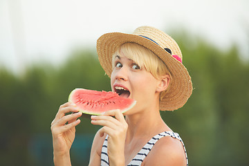 Image showing Beautiful girl in straw hat eating fresh watermelon. Film camera style