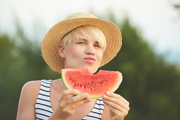 Image showing Beautiful girl in straw hat eating fresh watermelon. Film camera style