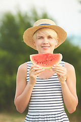 Image showing Beautiful girl in straw hat eating fresh watermelon. Film camera style