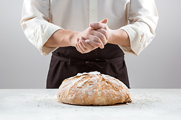 Image showing The male hands in flour and rustic organic loaf of bread