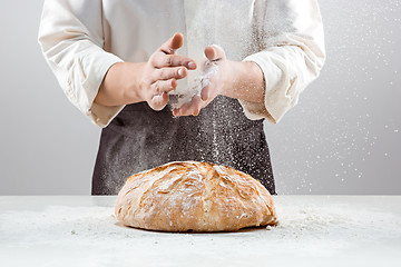 Image showing The male hands in flour and rustic organic loaf of bread