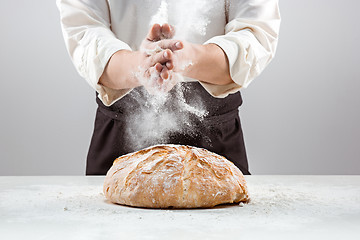 Image showing The male hands in flour and rustic organic loaf of bread