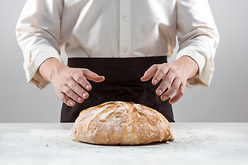 Image showing The male hands and rustic organic loaf of bread