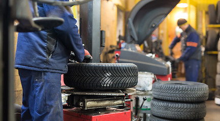 Image showing Professional auto mechanic replacing tire on wheel in car repair service.