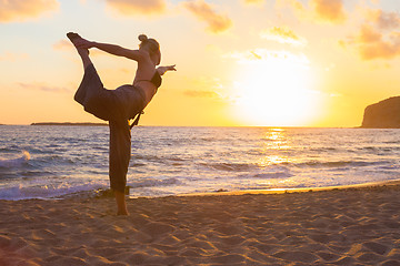 Image showing Woman practicing yoga on sea beach at sunset.