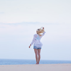 Image showing Woman on sandy beach in white shirt.