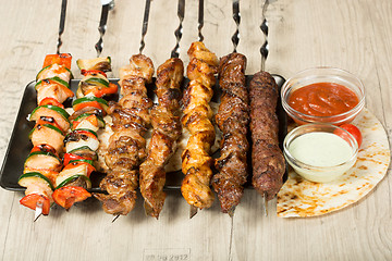 Image showing set shashlik. kebab skewer, black rectangular plate. sauce and onions