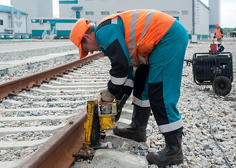 Image showing Worker establishes hydraulic jack for lifting rail