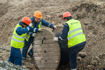 Image showing Workers pulling roll high voltage cable line