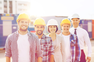 Image showing group of smiling builders in hardhats outdoors