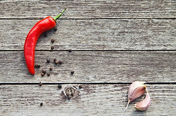 Image showing Red hot chili peppers with garlic on wood