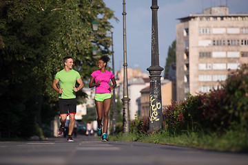 Image showing young smiling multiethnic couple jogging in the city