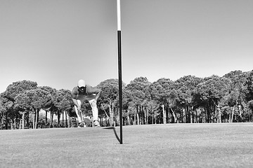 Image showing golf player hitting shot with club on course