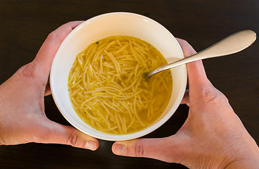 Image showing Female hands holding a bowl with European noodle soup