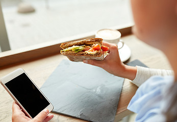Image showing woman with smartphone and sandwich at restaurant