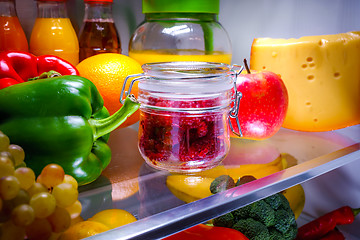 Image showing Fresh raspberries in a glass jar on a shelf open refrigerator