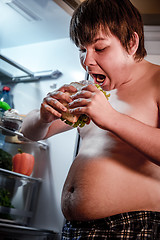 Image showing Hungry man holding a sandwich in his hands and standing next to 