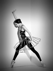 Image showing Ballerina in black outfit posing on pointe shoes, studio background.