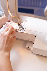 Image showing Woman sewing white cloth close-up