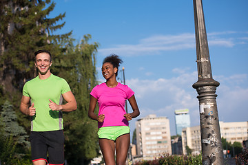 Image showing young smiling multiethnic couple jogging in the city