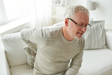 Image showing unhappy senior man suffering from backache at home