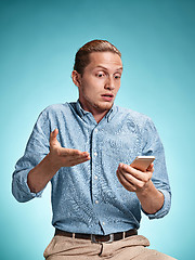 Image showing The young surprised caucasian man on blue background