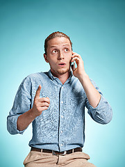 Image showing The young surprised caucasian man on blue background