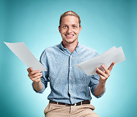 Image showing Smart smiling student with great idea holding sheets of paper
