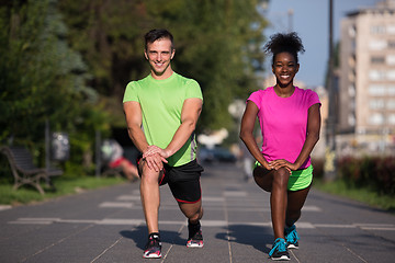 Image showing jogging couple warming up and stretching in the city