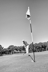 Image showing golf player hitting shot with club on course