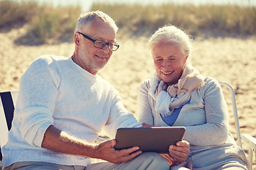 Image showing happy senior couple with tablet pc on summer beach