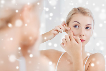 Image showing woman squeezing pimple at bathroom mirror