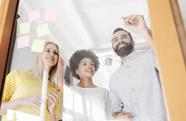 Image showing happy creative team writing on stickers at office