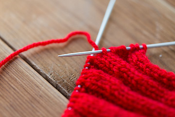 Image showing hand-knitted item with knitting needles on wood