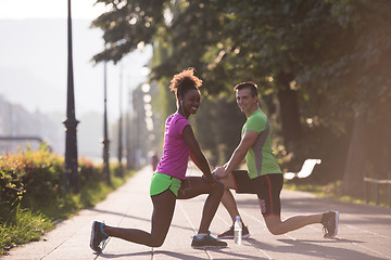 Image showing jogging couple warming up and stretching in the city