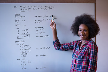 Image showing African American woman writing on a chalkboard in a modern offic