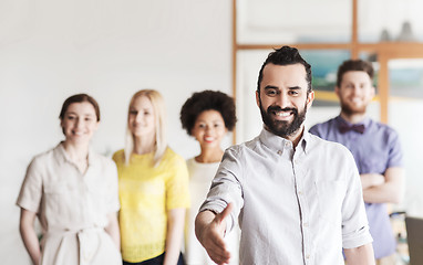 Image showing happy man making handshake over office team