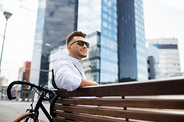 Image showing happy young man with bicycle sitting on city bench