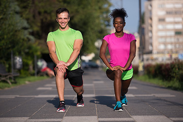 Image showing jogging couple warming up and stretching in the city