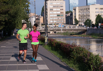 Image showing young smiling multiethnic couple jogging in the city