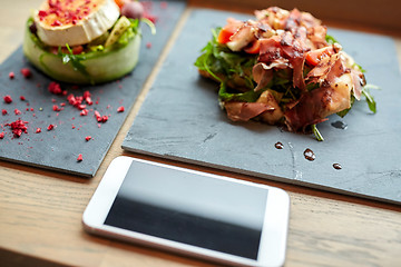 Image showing goat cheese and ham salads with smartphone at cafe