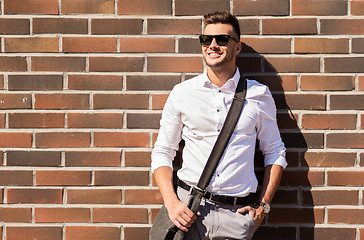 Image showing young man in sunglasses with bag over brickwall