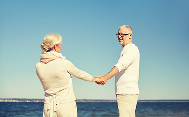 Image showing happy senior couple holding hands summer beach