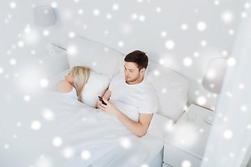 Image showing man texting message while woman is sleeping in bed