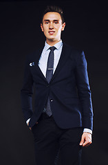 Image showing young pretty business man standing on black background, modern h