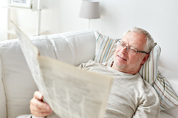 Image showing close up of senior man reading newspaper at home