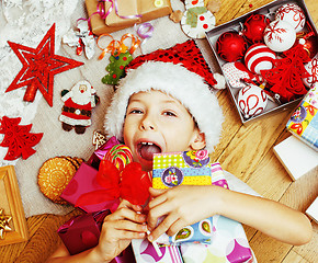 Image showing little cute kid in santas red hat with handmade gifts, toys vint