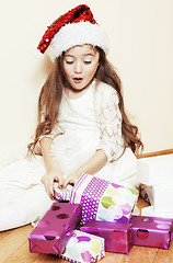 Image showing little cute girl in santas red hat waiting for Christmas gifts. 