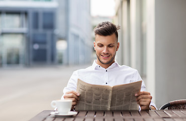 Image showing smiling man reading newspaper at city street cafe