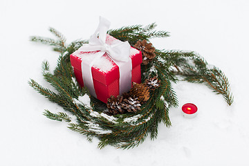 Image showing christmas gift and fir wreath with cones on snow